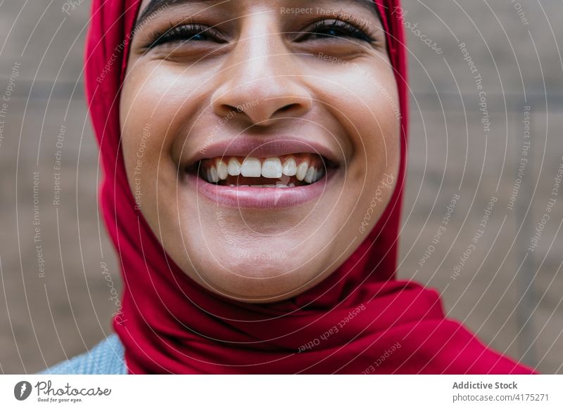 Entzückte ethnische Frau im Hidschab lacht in der Stadt Hijab Lachen muslimisch Vorschein charmant Gesichtsausdruck heiter Kopftuch Spaß haben arabisch Freude