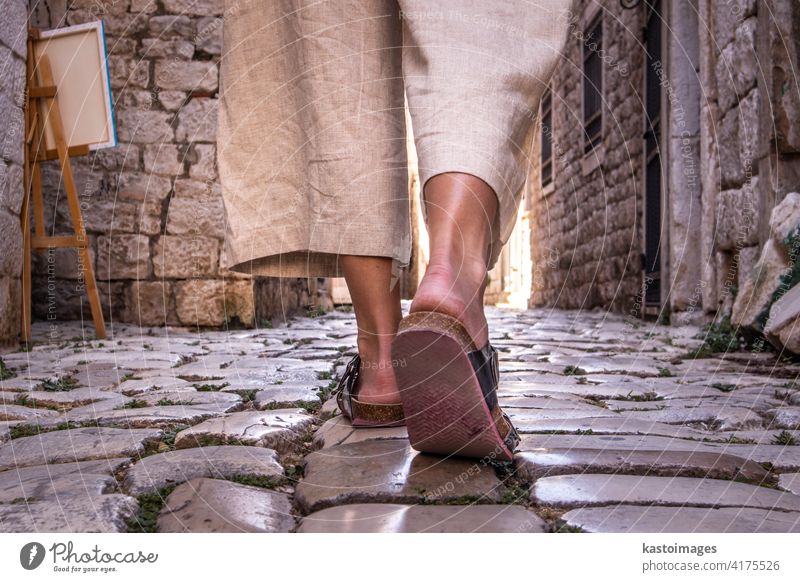 Detailaufnahme der weiblichen Beine tragen bequeme Reise Sandalen zu Fuß auf alten mittelalterlichen Kopfsteinpflaster Straße dring Sightseeing Stadtrundfahrt. Reisen, Tourismus und Abenteuer Konzept
