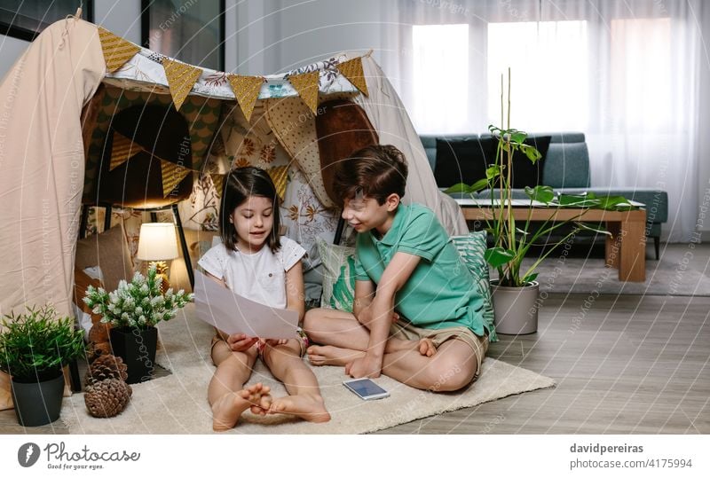 Junge und Mädchen spielen in einem diy Zelt zu Hause staycation Spaß zu Hause zu Hause bleiben Diy-Zelt heimwärts Wohnzimmer Familie Sperrung Glück Heimaturlaub
