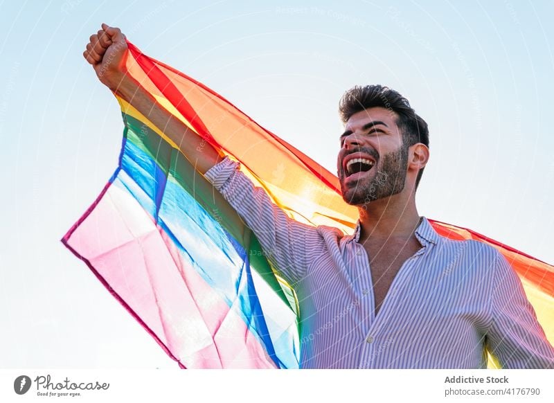 Optimistischer schwuler Mann mit LGBT-Fahne in der Stadt lgbt Homosexualität Regenbogen Straße expressiv schreien lgbtq männlich Stolz Toleranz heiter Großstadt
