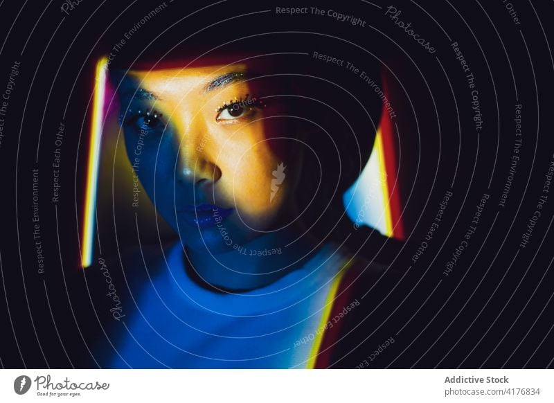 Modische Frau mit Make-up in Neon-Beleuchtung Stil Schönheit kreativ neonfarbig Porträt Model leuchten Schatten Menschliches Gesicht jung asiatisch ethnisch