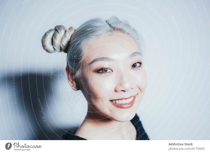 Ethnischer weiblicher Teenager, der an einer weißen Wand steht Frau Hipster informell jung Stil tausendjährig gefärbtes Haar asiatisch ethnisch modern urban