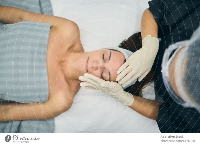 Kosmetikerin massiert das Gesicht eines Kunden im Salon Massage Schönheit Kosmetologie Dermatologie Leckerbissen Hautpflege Klient Tisch Pflege Lügen
