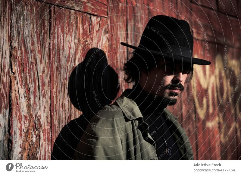 Hipster-Reisender mit Hut steht in der Nähe eines alten Gebäudes Mann Stil verwittert Landschaft schäbig trendy ländlich männlich jung angezogen Kopfbedeckung