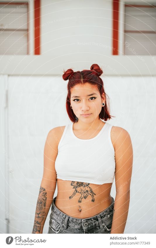 Junge ethnische Frau mit Tattoos schaut in die Kamera alternativ Piercing Stil informell Breakdance jung modern Subkultur Lifestyle schlank trendy