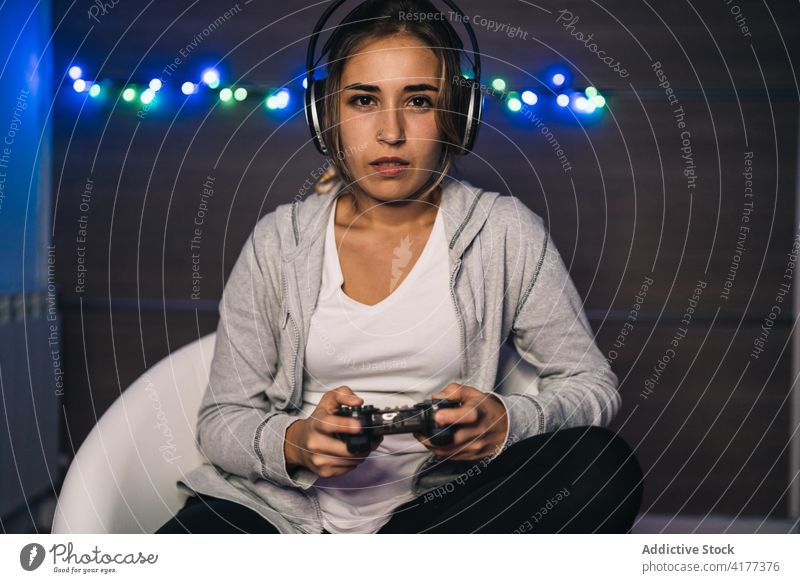 Gamer spielt Videospiel zu Hause Frau spielen Konsole Joystick Regler Spiel Spieler Gamepad Abend heimwärts Kopfhörer unterhalten sitzen online Armsessel