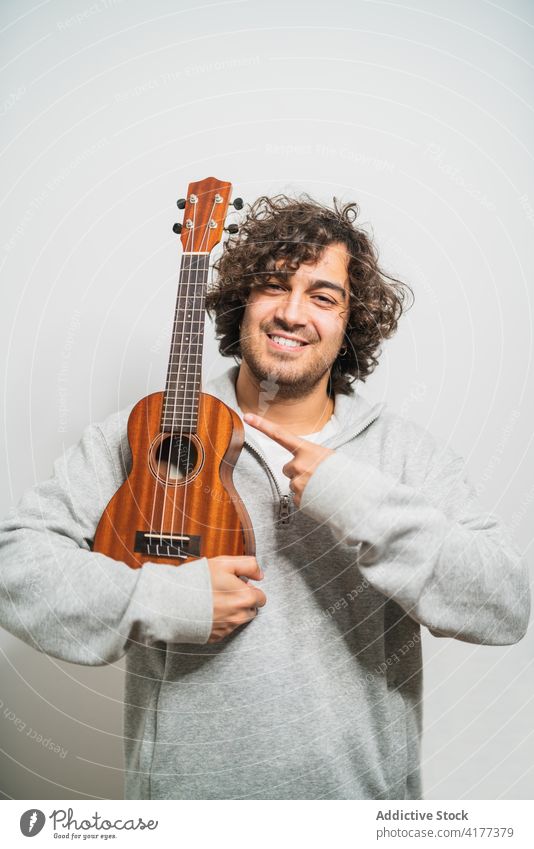 Fröhlicher Mann spielt Ukulele Gitarre spielen heiter Musiker ausführen positiv Instrument Glück jung ethnisch hispanisch männlich Melodie Lifestyle Gesang