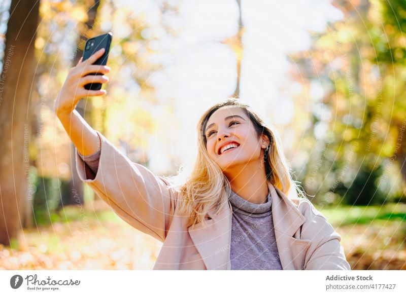 Frau macht Selfie mit Smartphone im Park Herbst Stil sich[Akk] entspannen unterhalten Selbstportrait fotografieren sonnig sitzen Wochenende soziale Netzwerke