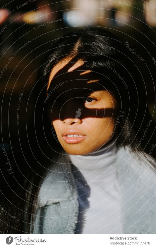 Ethnische Frau schützt ihr Gesicht im Park vor der Sonne Deckblatt Schatten Stil Model Sonnenlicht sonnig ethnisch trendy modern charmant feminin