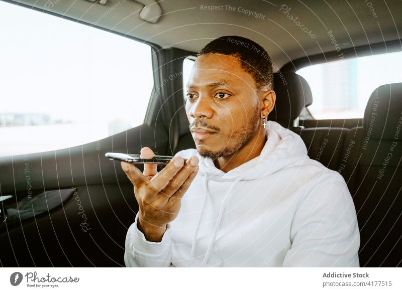 Schwarzer Mann nimmt Sprachnachricht im Auto auf Aufzeichnen Audio Nachricht Stimme PKW Smartphone Talkrunde Kommunizieren Fahrer männlich ethnisch schwarz