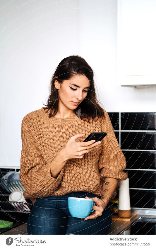 Frau trinkt Kaffee und surft auf dem Smartphone Browsen heimwärts Küche sich[Akk] entspannen Tasse Wochenende heimisch Abfertigungsschalter Internet Surfen