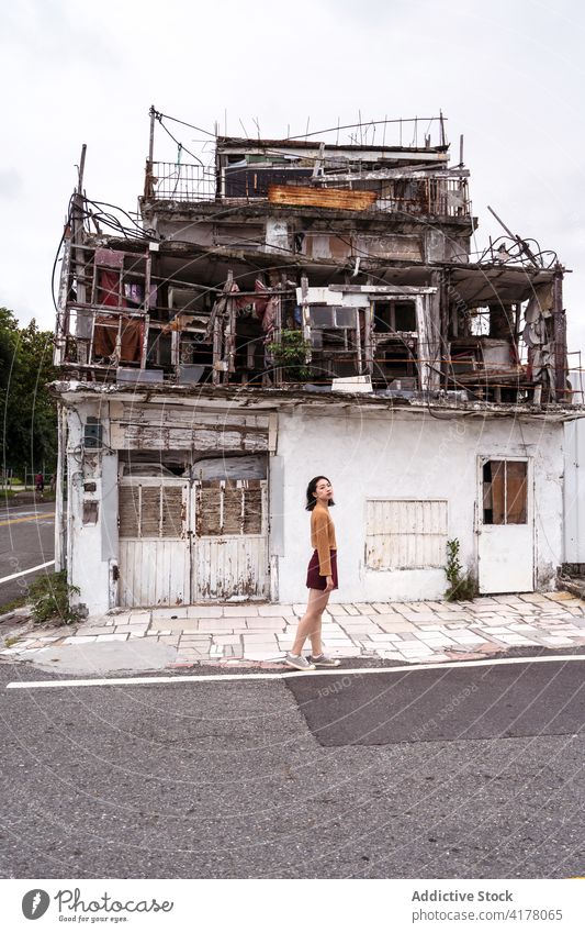 Frau steht in der Nähe eines verwitterten Gebäudes in der Stadt schäbig Straße gealtert Grunge Verlassen Außenseite antik Ostküste Struktur tagsüber Großstadt