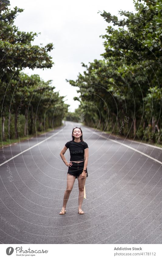 Junge Frau steht auf einer asphaltierten Straße im Wald Park Reisender positiv Weg Natur erkunden jung asiatisch ethnisch kenting Taiwan aktiv Baum Glück
