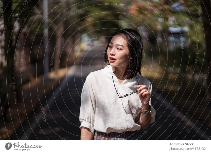 Stilvolle Frau steht auf einer Allee im Stadtpark Park Fahrrad Fahrspur sonnig schlendern genießen sorgenfrei Weg Sommer asiatisch ethnisch