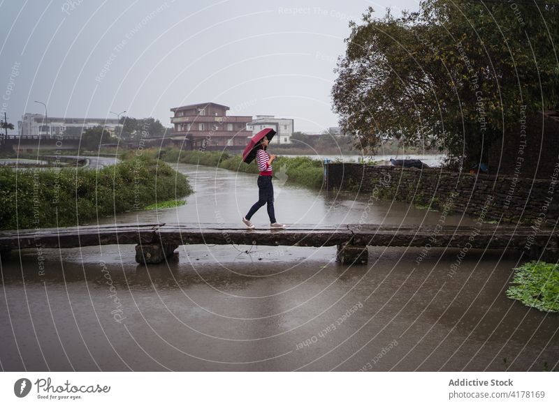 Frau geht an einem regnerischen Tag unter einem Regenschirm spazieren Einsamkeit Großstadt genießen Brücke durchkreuzen trist Melancholie Kreis Yilan Taiwan