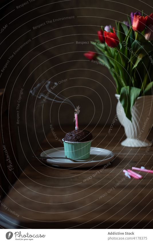 Schokoladen-Cupcake mit Kerze auf Tisch mit Blumen festlich Geburtstag Lebensmittel Gebäck süß Dessert feiern Feiertag Veranstaltung lecker Blumenstrauß