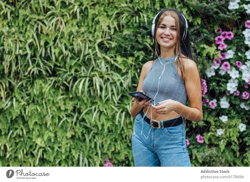 Glückliche Frau mit Smartphone und Kopfhörern, die im Park chillt zuhören Spaß haben heiter Sommer Telefon Mobile Musik positiv jung Apparatur Gerät Lifestyle