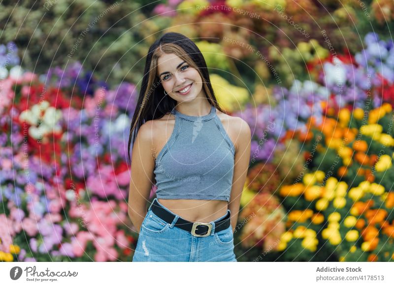 Junge Frau steht in der Nähe von blühenden Blumen Park jung lässig farbenfroh Lifestyle Blütezeit tausendjährig modern Frühling Sommer Natur Dame Zeitgenosse