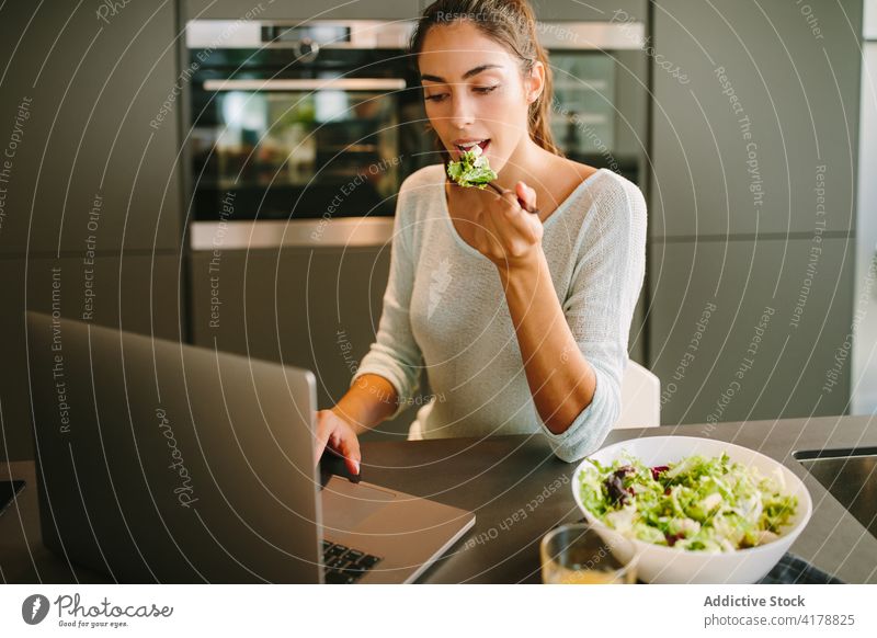 Frau isst Salat und arbeitet am Laptop in der Küche essen freiberuflich Salatbeilage Mittagessen heimwärts abgelegen Unternehmer Projekt Getränk frisch