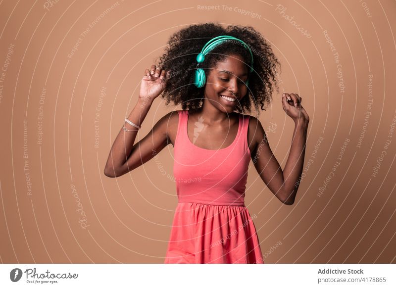 Ethnische Frau mit Kopfhörern tanzt im Studio Tanzen Spaß Musik Glück Stil Atelier farbenfroh Frisur Afro-Look ethnisch Kubaner Afroamerikaner schwarz Lächeln