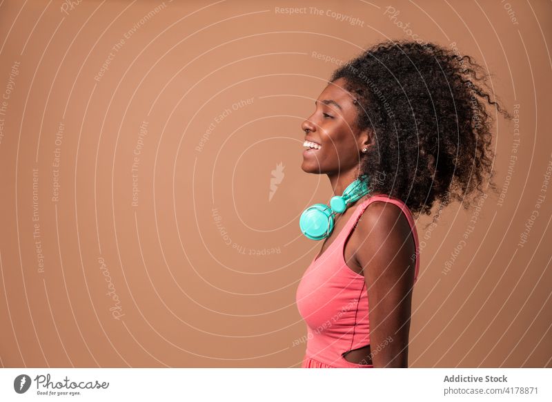 Ethnische Frau mit Kopfhörern im Studio stehend Spaß Musik Glück Stil Atelier farbenfroh Frisur Afro-Look ethnisch Kubaner Afroamerikaner schwarz Lächeln trendy
