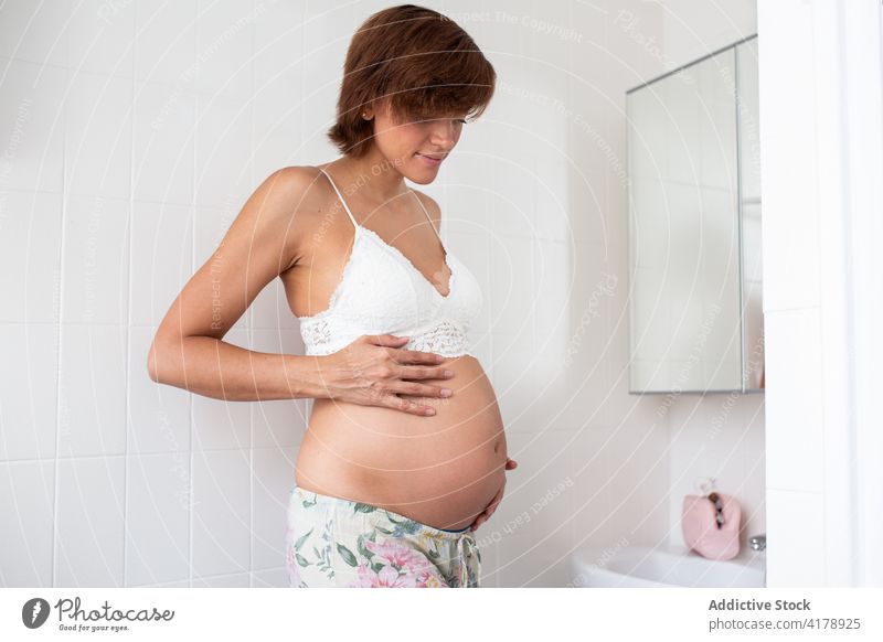 Ruhige schwangere Frau im BH im Badezimmer berühren Bauch erwarten Angebot Schwangerschaft Magen mütterlich Mutter Unterleib vorwegnehmen hell Mutterschaft