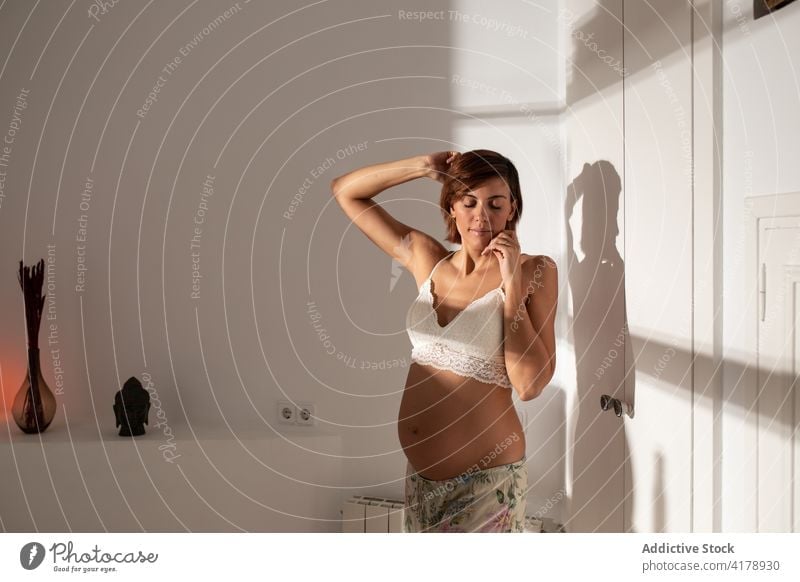 Schwangere Frau streckt sich morgens im Zimmer Dehnung wach schwanger Morgen Arme hochgezogen genießen Bauch Schwangerschaft Sonnenlicht erwarten sorgenfrei