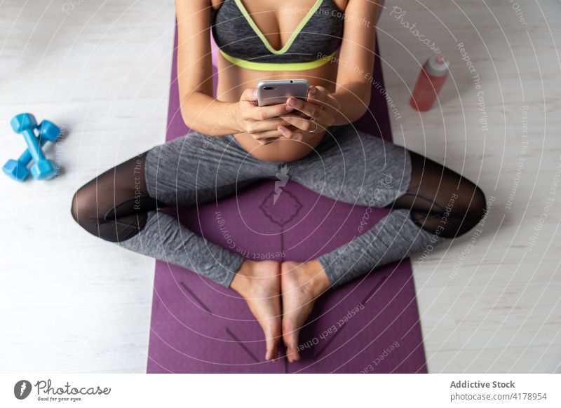 Schwangere Frau am Handy, während sie sich vom Yoga ausruht schwanger meditieren sich[Akk] entspannen ruhig Pose Sportbekleidung Unterlage Harmonie Wohlbefinden