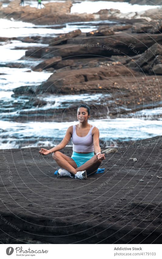 Entspannte Frau macht Yoga in Lotus-Pose am Meeresufer meditieren Strand padmasana Mudra Achtsamkeit Zen friedlich Harmonie üben Gesundheit Gleichgewicht Ufer