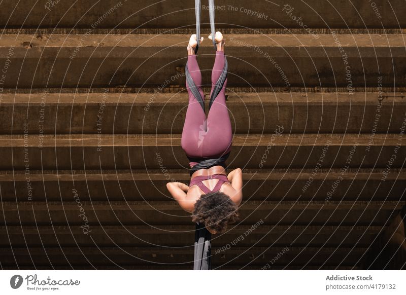 Schlanke Frau macht Aerial Yoga in der Stadt Antenne Split Pose üben Seide beweglich Gleichgewicht Gurt Großstadt ethnisch schwarzer Hintergrund Afroamerikaner