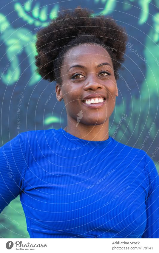 Schwarze Frau steht an einer Wand mit Graffiti Großstadt fettarm sich[Akk] entspannen urban cool Straßenkunst Lächeln ethnisch schwarz Afroamerikaner farbenfroh