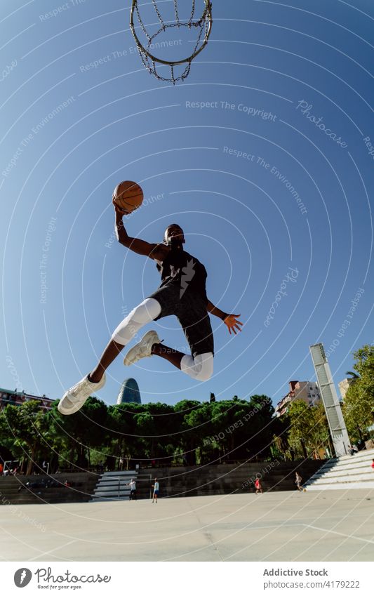 Afroamerikanischer Sportler spielt Basketball auf dem Platz Spieler springen Reifen Ball spielen Sportpark punkten Gericht männlich ethnisch schwarz