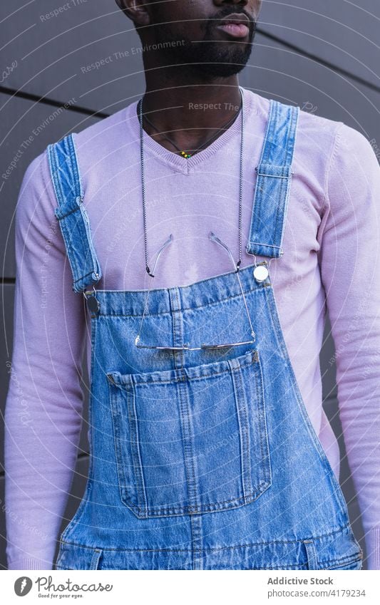 Stylischer schwarzer Mann in Latzhose gesamt Stil trendy Großstadt cool urban Jeanshose Jeansstoff Straße männlich ethnisch Afroamerikaner Sweatshirt modern