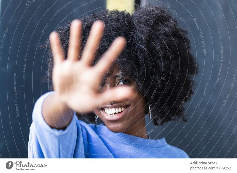 Lächelnde schwarze Frau, die ihr Gesicht vor der Kamera verdeckt Tierhaut Deckblatt nein heiter ablehnen ausdehnen positiv Afro-Look jung Afroamerikaner