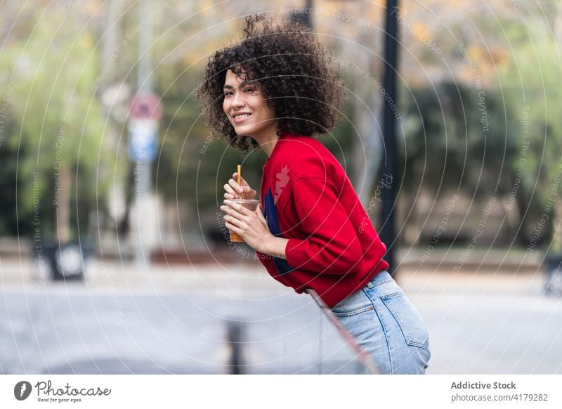 Lächelnde schwarze Frau mit Becher mit Saft zum Mitnehmen auf der Straße Imbissbude Großstadt genießen Wochenende Kunststoff sich[Akk] entspannen ethnisch