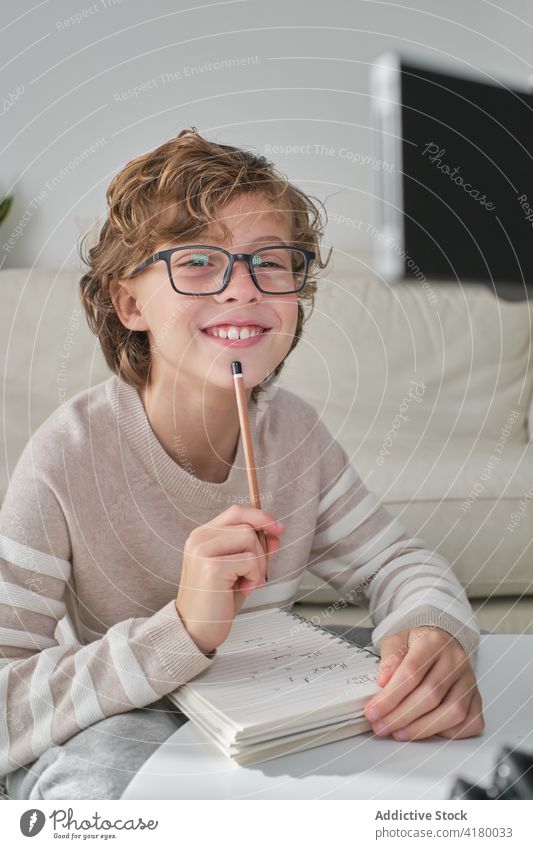 Ausdrucksstarkes Jungenportrait Porträt kleiner Junge in die Kamera schauen expressiv zu Hause gemütlich schreibend mitschreibend heiter Brille Denken Gedanken