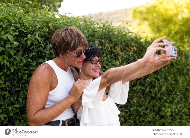Lächelnde Frauen nehmen Selfie im Park Freund Zusammensein Gedächtnis Sommer genießen Selbstportrait Smartphone Erwachsener grün Mobile Telefon Stil heiter