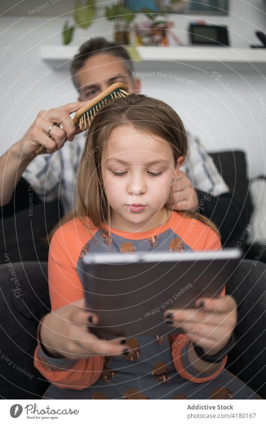 Vater kämmt das Haar seiner Tochter Kamm Bürste Behaarung Pflege Liebe Kind vorsichtig Papa Tablette benutzend Zusammensein Eltern Partnerschaft Lifestyle