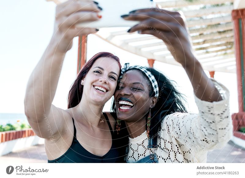 Glückliches lesbisches Paar macht Selfie mit Smartphone Frauen Zusammensein lgbt Partnerschaft Liebe Handy Freundin rassenübergreifend multiethnisch vielfältig