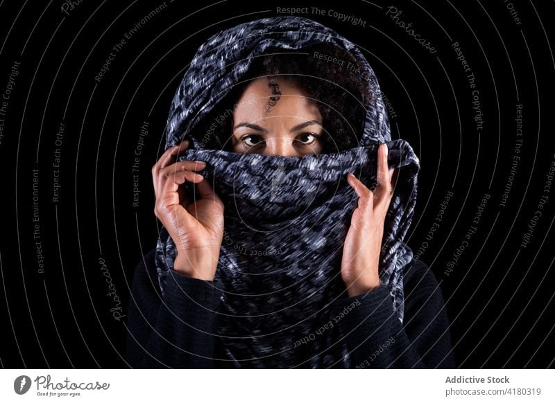 Ethnische Frau bedeckt Gesicht mit Kopftuch Deckblatt Tierhaut ethnisch Konzept ernst Porträt Angst Kultur jung schwarz Afroamerikaner Auge Lifestyle Missbrauch