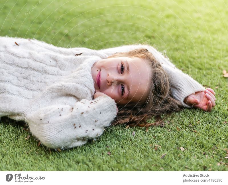 Unbeschwertes Mädchen liegt im Gras im Hinterhof Lächeln Grasland niedlich heiter sorgenfrei Lügen Wiese Natur positiv Optimist schön Freizeit Kindheit