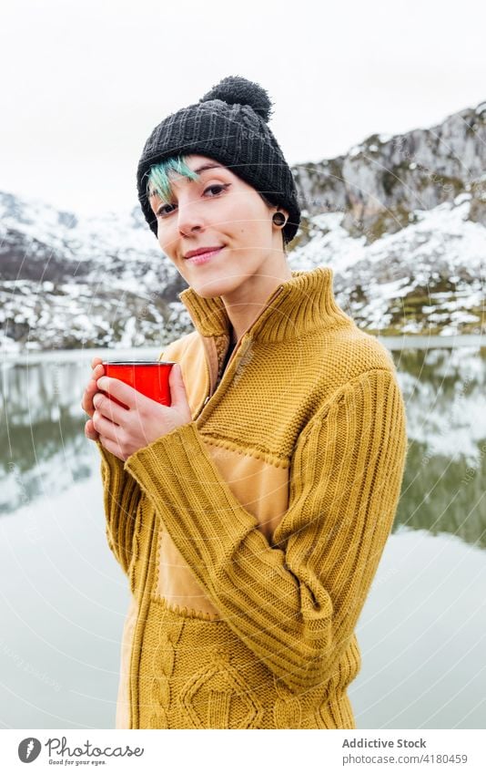 Gelassene Frau genießt heißes Getränk in der Nähe eines Sees in bergigem Terrain Berge u. Gebirge trinken Heißgetränk Gelassenheit genießen friedlich Winter
