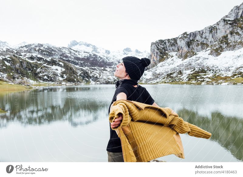 Glückliche Frau steht mit ausgestreckten Armen am kalten Seeufer Berge u. Gebirge ausdehnen Freiheit Freude Hochland Reisender aufgeregt genießen felsig Winter