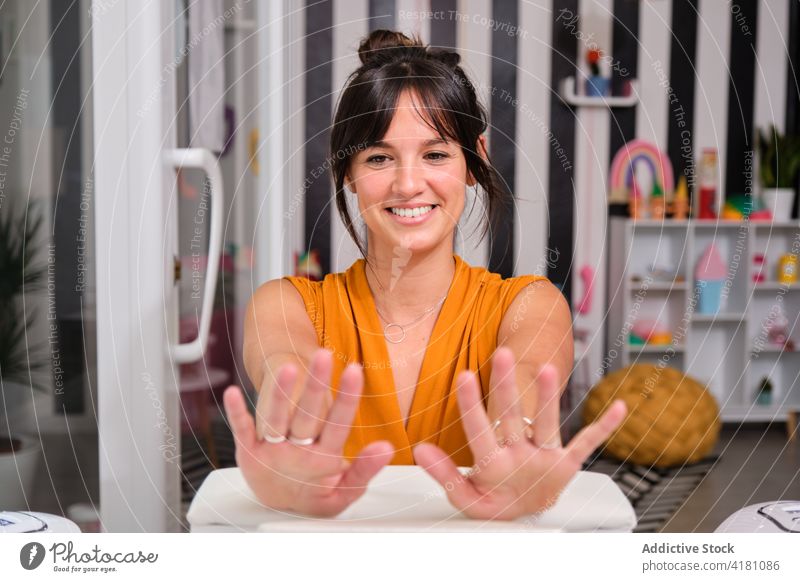 Glückliche Frau zufrieden mit Maniküre im Salon Klient Lächeln Schönheit heiter Finger Hand nageln professionell Dienst Leckerbissen Freude froh Lifestyle