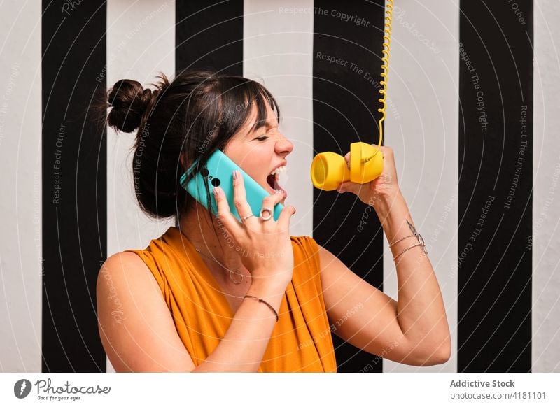 Lustige Frau mit Smartphone und Retro-Telefonhörer Kommunizieren Gerät zuhören reden Schrei schreien lustig jung Anruf Apparatur Mobile Anschluss Gespräch