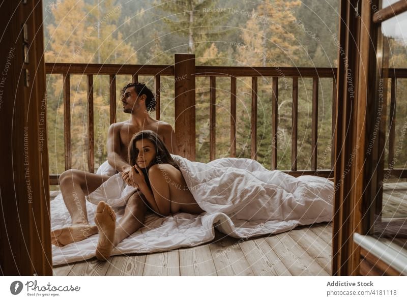 Gelassenes nacktes Paar auf Decke liegend auf Veranda Terrasse kuscheln Herbst Saison Bonden Umarmung sich[Akk] ausziehen Zuneigung Zusammensein romantisch