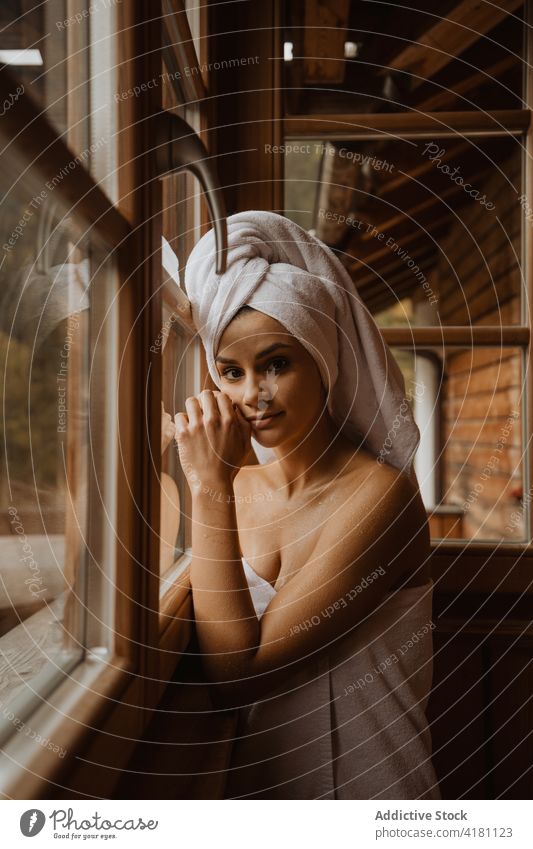 Charmante Frau in Handtüchern, die sich im Hüttenfenster spiegeln Gesicht berühren feminin sanft Angebot Handtuch Reflexion & Spiegelung Fenster Kabine