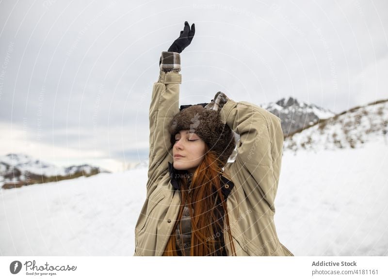 Verträumter Reisender in Oberbekleidung vor verschneitem Berg Augen geschlossen atmen genießen Berge u. Gebirge Schnee Harmonie idyllisch Winter Frau