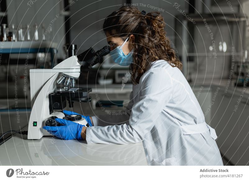 Forscher bei der Arbeit mit einem Mikroskop in einem biotechnologischen Labor Wissenschaftler Experiment forschen untersuchen Gerät analysieren Chemikalie Frau