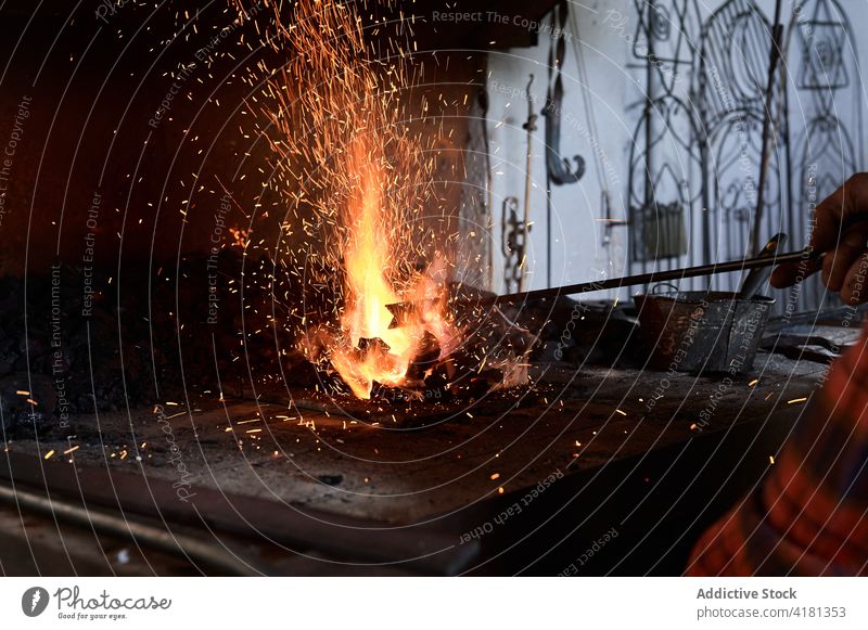 Der Schmied erhitzt Metall auf einer Flamme Mann erwärmen Stab Feuer schmieden Hufschmied Arbeit Werkstatt Metallbearbeitung Brandwunde Funken männlich